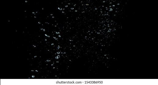 Blurry images of soda water bubbles splashing and floating up to top of water surface which little and big circle texture shaped up by gas power in carbonate drink make refreshing on black background