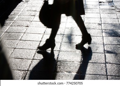 Blurry Legs Of A Young Woman Walking On The City Sidewalk In The Night In Black And White