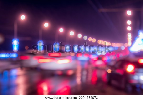 Blurry lights of\
moving cars and lanterns reflecting on the wet asphalt in the night\
city. Abstract bright\
bokeh.