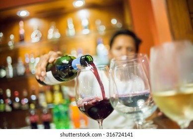 Blurry Man pouring red wine into glass with white wine foreground, selective focus. - Powered by Shutterstock