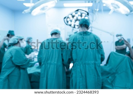 Blurry medical team of surgeons in hospital working surgical intervention.Surgery operating room with electrocautery equipment for cosmetic surgery.Surgeon gloved hands hold the instruments.