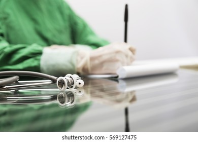 Blurry Medicine Doctor's Working And Doctor Taking  Patient Notes With  And Stethoscope On  Table. Doctor Concept In Hotpital.Split Tone Instagram Like.With Light Processed.