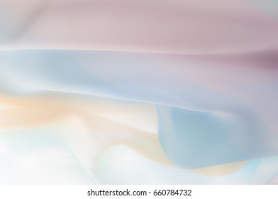Blurry, not sharp sharpness Texture, background, pattern. Silk fabric is transparent, yellow-pink green in blue. Abstract soft chiffon texture background. 