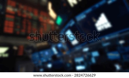A blurry out of focus view of multiple computer screens and electronic displays showing stock market tickers and financial analytics in a trading room environment.