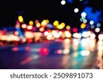 A blurry photo of a busy street at night with cars and lights. Scene is busy and chaotic, with the lights and reflections creating a sense of movement and energy