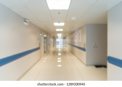 Blurry Photo Of Hospital Walk Way With Bright Clean Lighting. White Floor With Warm Tone Orange Color In The Middle Of Picture. Use For Background Purpose. Medical And Insurance Concept.