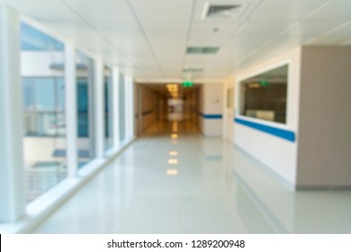 Blurry Photo Of Hospital Walk Way With Bright Clean Lighting. White Floor With Warm Tone Orange Color In The Middle Of Picture. Use For Background Purpose. Medical And Insurance Concept.