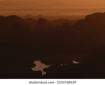 A blurry photo of a mountain range with a lake in the foreground. The sky is orange and the mountains are in the background - Powered by Shutterstock