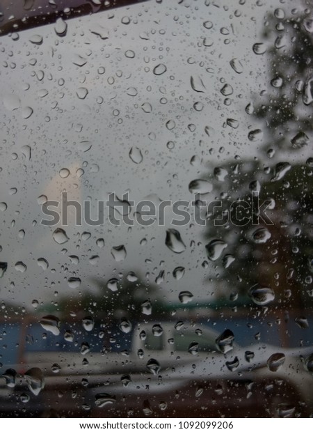 Blurry rain droplets or water droplets on glass or\
mirror of car on road