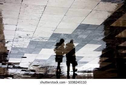 Blurry Reflection Shadow Of A Man And Woman Walking Together The City Street Patterned Sidewalk On A Dark Rainy Day