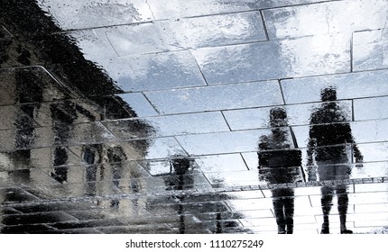 Blurry reflection shadow silhouettes of couple walking on dark rainy city street - Powered by Shutterstock