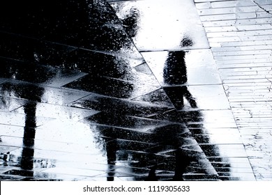 Blurry reflection  silhouette of one person  walking alone  on wet city park sidewalk on a rainy day - Powered by Shutterstock