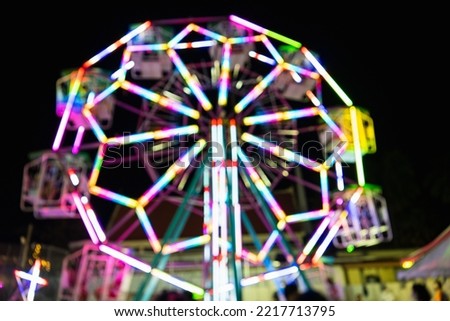 Blurry rollercoaster in bokeh, Ferris wheel at night of colorful with outdoor, Defocused (blurred) and blur image of Amusement park, The annual temple event has activities. Image out of focus