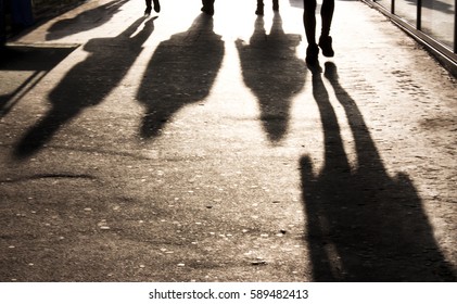 Blurry shadows of people walking towards the camera on the city sidewalk