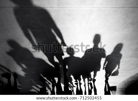 Blurry shadows silhouette of people walking towards the camera on black and white