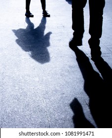 Blurry Silhouette Shadows Of A Man And A Woman Walking Toward Each Other On City Street In The Night