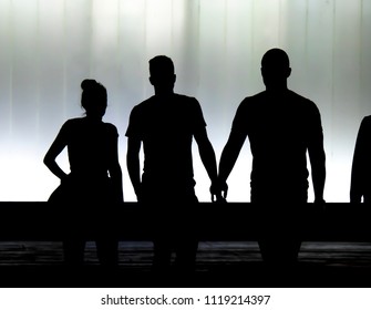 Blurry Silhouettes Of Three Young Friends Students Walking In Front Of The Modern Building In The Black And White Night