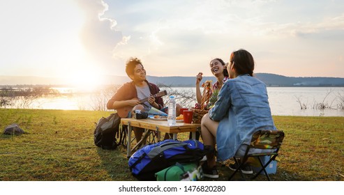 blurry and soft focus of group of Asian friends tourist drinking and playing guitar together with happiness in Summer while having camping near lake at sunset - Shutterstock ID 1476820280