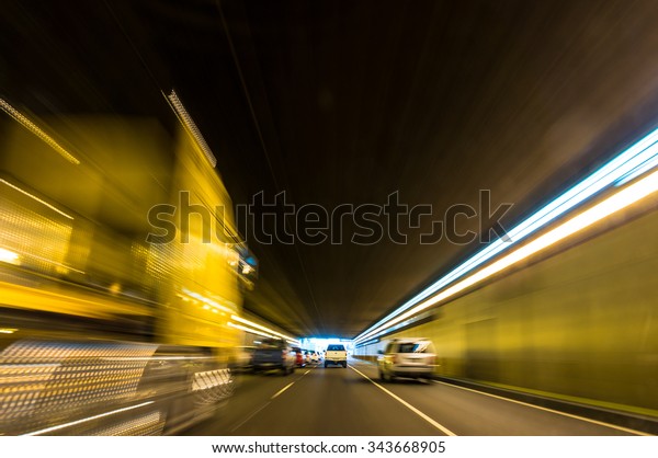 Blurry\
speeding car in a tunnel with light trails moving toward light.\
Motion blur visualizes the speed and\
dynamics.