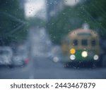 A blurry street through a rain-spattered window, with the iconic old-fashioned a Melbourne city circle tram car on street. Concept of quiet mood of a rainy day, solitude and feeling of urban life
