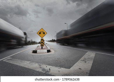 Blurry Trucks With Fork In The Road Sign.