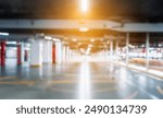 blurry underground parking road in basement. Empty open car parking garage with orange sunlight reflecting 