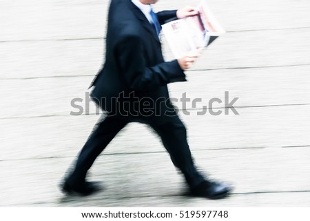 blurry to view of businessman walking by reading the newspaper