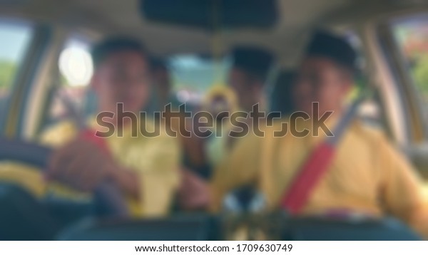 Blurry view of south east asian Muslim family in\
a car on a traditional trip back home (pulang kampung) during Eid\
al-Fitr holiday.