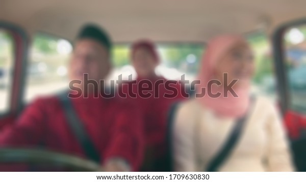 Blurry view of south east asian Muslim family in\
a car on a traditional trip back home (pulang kampung) during Eid\
al-Fitr holiday.