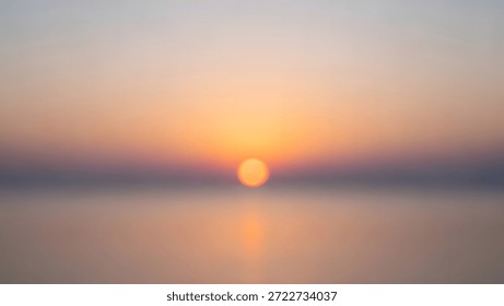 A blurry view of the sun setting over the ocean with a colorful sky.