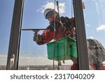 A blurry view through a dirty window of a window washer. Rope access. An alpinist washes windows