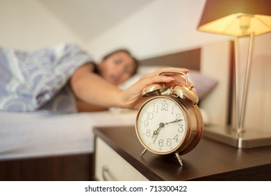 Blurry Woman Waking Up Late In The Morning With Closeup Of Alarm Clock