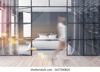 Blurry Young Woman Walking In Stylish Bedroom With Gray Walls, Wooden Floor, Comfortable King Size Bed And Glass Doors. Toned Image Double Exposure