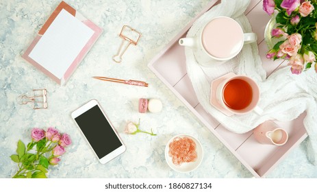 Blush pink theme cosy hygge desktop workspace with keyboard smart phone tea and rose on a stylish white marble textured background. Top view blog hero header creative flat lay. Negative copy space.