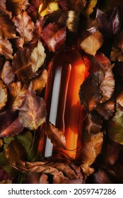 Blush Wine Bottle Laying In A Filed Of Autumn Leaves. High Angle Shot With Strong Side Light And Vivid Colors. Thanksgiving Wine Suggestions.