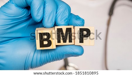BMP Basic metabolic panel - word from wooden blocks with letters holding by a doctor's hands in medical protective gloves. Medical concept.