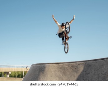 BMX bicycle rider flying and doing stunt No Hand in quarter pipe. Skilled BMX freestyler athlete jumping over quarter ramp and doing aerial trick No Hand in street ramp park outdoors - Powered by Shutterstock