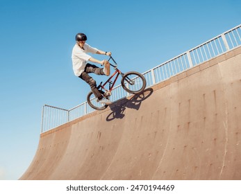 BMX bicycle rider flying and doing stunt Can-Can in wooden quarter pipe. Skilled BMX freestyler athlete jumping and doing aerial trick Can-Can in street wooden half-pipe ramp park - Powered by Shutterstock