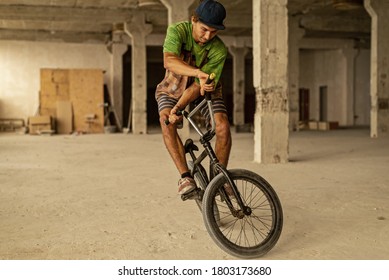 A BMX cyclist doing a jump stunt in an abandoned factory building. Extreme cycling. Urban free ride. BMX - bicycle motocross. - Powered by Shutterstock