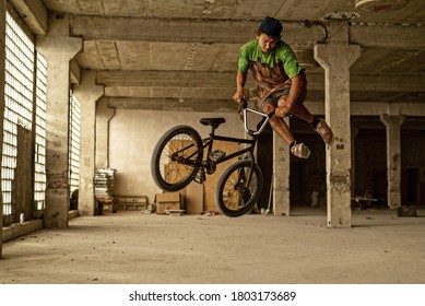 A BMX cyclist doing a jump stunt in an abandoned factory building. Extreme cycling. Urban free ride. BMX - bicycle motocross. - Powered by Shutterstock