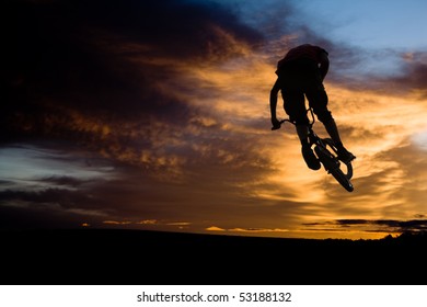 bmx rider at jump against sky at sundown