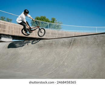 BMX rider performing aerial trick Toboggan on concrete quarter pipe in skatepark. Skilled BMX freestyler jumping over quarter pipe ramp skatepark. Young BMX bicycle rider having fun and posing. Copy - Powered by Shutterstock