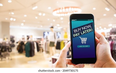 BNPL Buy now pay later online shopping concept.Hands holding mobile phone on blurred store as background