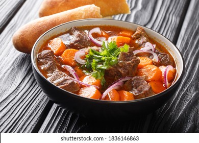 Bo Kho beef ragout in spicy sauce with carrots served with Vietnamese bread close-up in a bowl on the table. horizontal