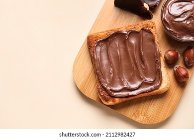 Board of bread with chocolate paste and hazelnuts on beige background, closeup - Shutterstock ID 2112982427