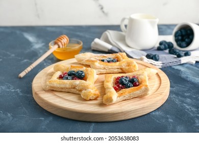 Board With Danish Pastry On Color Background