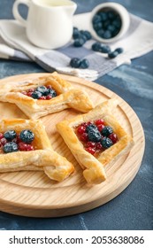 Board With Danish Pastry On Color Background