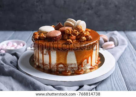 Board with delicious caramel cake on table