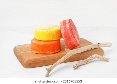 Board with different handmade solid shampoo and branches on light background, closeup
