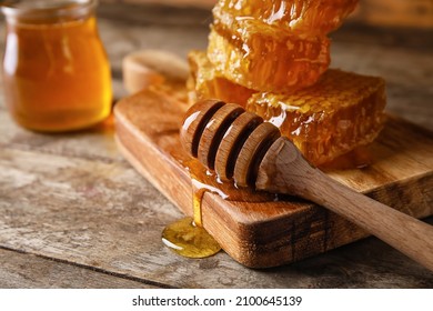 Board with dipper and honey combs on wooden background, closeup
